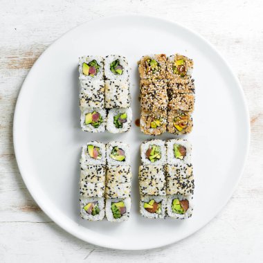 Geleneksel suşi ruloları ve susamlı maki, avokado ve balık. Japon yemeği. Üst Manzara. Beyaz bir arkaplanda.
