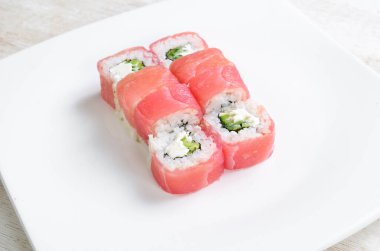 Suşi, avokado ve somonla birlikte beyaz tabakta yuvarlanıyor. Üst Manzara. Beyaz bir arkaplanda.