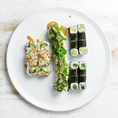 Geleneksel Japon suşisi beyaz tabakta yuvarlanır. Üst Manzara. Asya yemekleri. Beyaz bir arkaplanda.