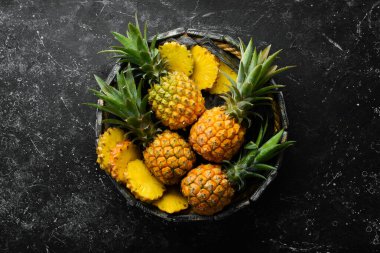 Siyah taşlı arka planda tatlı bebek ananası. Tropik meyveler. Üst Manzara. Metin için boş alan.