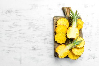Ananas koleksiyonu. Beyaz ahşap arka planda tam ve dilimlenmiş ananas. Üst Manzara. Metin için boş alan.
