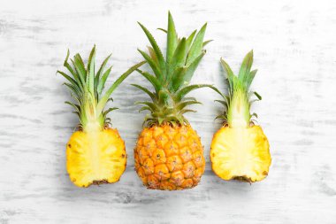 Ananas koleksiyonu. Beyaz ahşap arka planda tam ve dilimlenmiş ananas. Üst Manzara. Metin için boş alan.