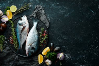 Siyah taş tabakta baharatlı iki dorado balığı. Karanlık bir arka planda. Üst görünüm.