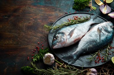 Siyah taş tabakta baharatlı iki dorado balığı. Karanlık bir arka planda. Üst görünüm.