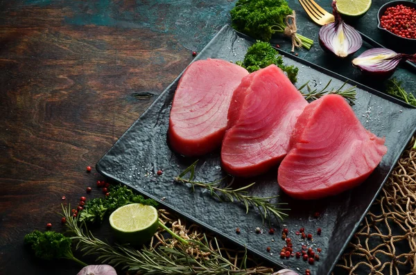 Siyah bir tabakta taze sulu ton balığı bifteği. Karanlık bir arka planda. Üst görünüm.