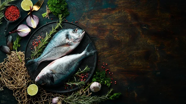 Två Doradofisk Med Kryddor Svart Stenplatta Mörk Bakgrund Ovanifrån — Stockfoto