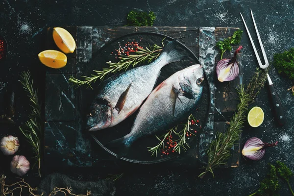 Две Рыбки Дорадо Специями Черной Каменной Тарелке Тёмном Фоне Вид — стоковое фото