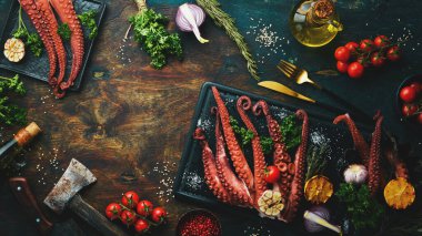 Fırında ahtapot, limon, sarımsak ve maydanozla siyah tahta üzerinde. Üst Manzara. Düz yatıyordu.