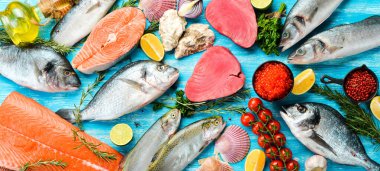 Deniz ürünleri arka planı: somon, ton balığı, havyar, istiridye, dorado balığı ve mavi ahşap arka planda kabuklu deniz ürünleri. Üst Manzara. Deniz ürünleri..