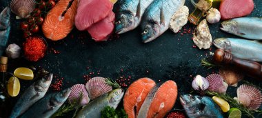 Siyah taştan bir zemin üzerinde deniz ürünleri: somon, ton balığı, havyar, istiridye, dorado balığı ve mavi ahşap zemin üzerinde kabuklu deniz ürünleri. Deniz ürünleri. Düz yatıyordu.