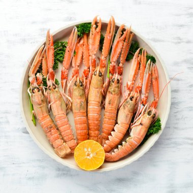 Maydanozlu kaynamış Langoustines ve bir tabak baharat. Beyaz ahşap arka planda Norveç ıstakozu. Üst Manzara. Boş kopyalama alanı.