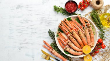 Maydanozlu kaynamış Langoustines ve bir tabak baharat. Beyaz ahşap arka planda Norveç ıstakozu. Üst Manzara. Boş kopyalama alanı.