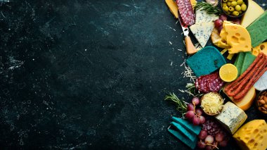 Renkli peynir, sosis, salam ve atıştırmalık. Karanlık bir arka planda. Bedava fotokopi. Üst görünüm.
