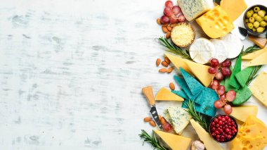 Tahta üzerinde peynir: Brie, mavi peynir, parmesan ve maasdam. Beyaz ahşap bir arka planda. Bedava fotokopi. Üst görünüm.