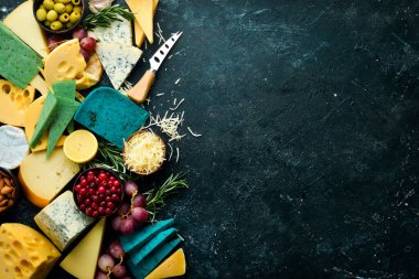 Büyük bir peynir seti, fındık, üzüm ve atıştırmalık siyah taş arka planda. Bedava fotokopi. Üst görünüm.