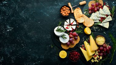 Peynir. Tabaklarda peynir dilimleri: Brie, blue, gorgonzola, parmesan ve siyah taşlı arka planda maasdam. Bedava fotokopi. Üst görünüm.