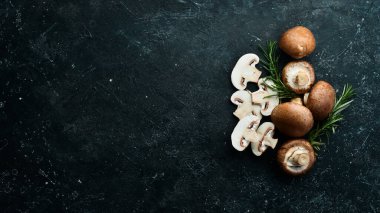 Siyah taşlı arka planda taze şampiyon mantarları. Kırsal tarzda. Üst görünüm.