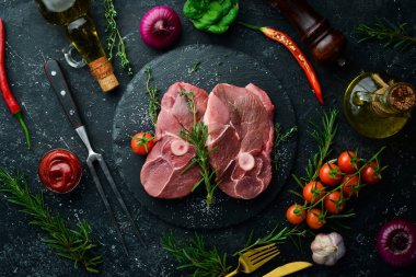 Biberiye ve baharatlı çiğ kemiksiz kuzu bifteği. Karanlık bir arka planda. Üst görünüm.