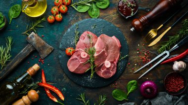 Biberiye ve baharatlı çiğ kemiksiz kuzu bifteği. Karanlık bir arka planda. Üst görünüm.