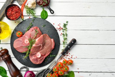 - Et. Biberiye ve baharatlı çiğ kemiksiz kuzu bifteği. Beyaz ahşap bir arka planda. Üst görünüm.