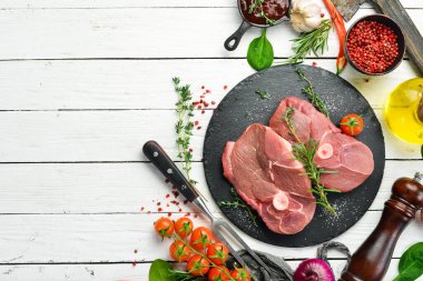 - Et. Biberiye ve baharatlı çiğ kemiksiz kuzu bifteği. Beyaz ahşap bir arka planda. Üst görünüm.