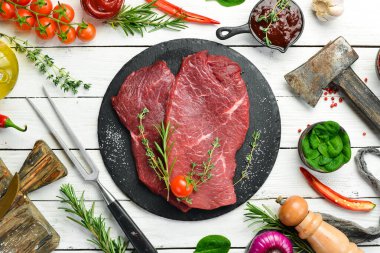 Biberiye ve baharatlı iki parça taze çiğ dana eti. Beyaz ahşap bir arka planda. Üst görünüm.