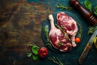 Biberiye ve baharatlı iki çiğ ördek budu. Siyah taş arka planda. Üst görünüm.