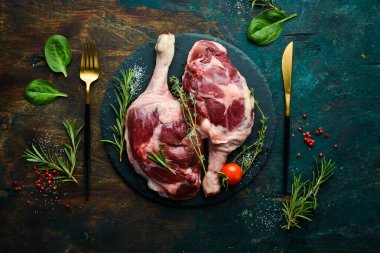 Biberiye ve baharatlı iki çiğ ördek budu. Siyah taş arka planda. Üst görünüm.