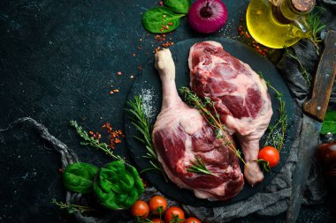 Biberiye ve baharatlı iki çiğ ördek budu. Siyah taş arka planda. Üst görünüm.