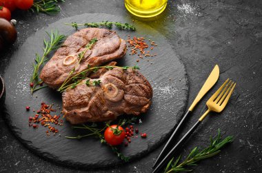 Baharatlı ve biberiyeli ızgara kuzu biftek. Barbekü eti. Üst Manzara. Siyah taş kesme masasının üstünde düz bir görünüm vardı..