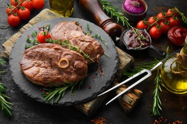 Baharatlı ve biberiyeli ızgara kuzu biftek. Barbekü eti. Üst Manzara. Siyah taş kesme masasının üstünde düz bir görünüm vardı..