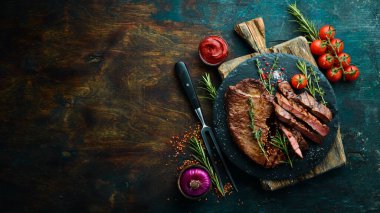 Baharatlı sulu dana biftek, kekik ve biberiye. Üst Manzara. Siyah taş kesme masasının üstünde düz bir görünüm vardı..