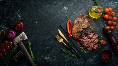 Baharatlı sulu dana biftek, kekik ve biberiye. Üst Manzara. Siyah taş kesme masasının üstünde düz bir görünüm vardı..