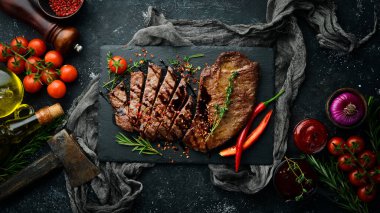 Baharatlı sulu dana biftek, kekik ve biberiye. Üst Manzara. Siyah taş kesme masasının üstünde düz bir görünüm vardı..