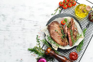 Biftek. Dana eti, baharatlı et ve beyaz ahşap arka planda sebze. Düz yatıyordu. Üst görünüm.