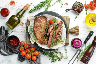 Biftek. Dana eti, baharatlı et ve beyaz ahşap arka planda sebze. Düz yatıyordu. Üst görünüm.