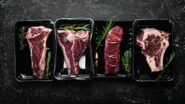 Vakumlu paketlenmiş biftek seti. Piyasa. Üst Manzara. Siyah taş kesme masasının üstünde düz bir görünüm vardı..