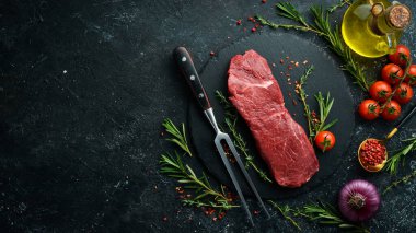 Kekik, biberiye ve baharatlı çiğ sığır filetosu. Üst Manzara. Siyah taş kesme masasının üstünde düz bir görünüm vardı..