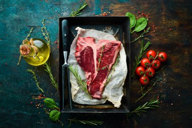 Kekik, biberiye ve baharatlı bir taş masada çiğ biftek. Üst Manzara. Siyah taş kesme masasının üstünde düz bir görünüm vardı..