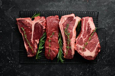 Çiğ siyah Angus Prime bifteği: T-bone, striploin, Rib, New York bifteği. Üst Manzara. Taş bir arka planda.