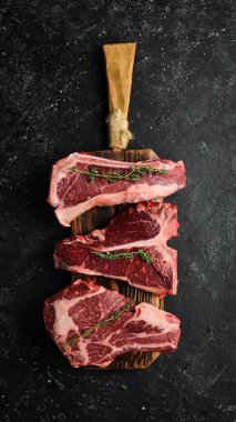 Çiğ siyah Angus Prime bifteği: T-bone, striploin, Rib, New York bifteği. Üst Manzara. Taş bir arka planda.