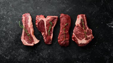 Çiğ siyah Angus Prime bifteği: T-bone, striploin, Rib, New York bifteği. Üst Manzara. Taş bir arka planda.