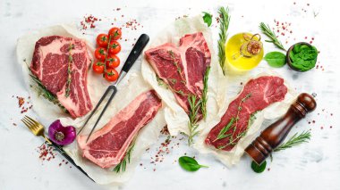 Çiğ biftek seti: biftek, striploin, pirzola, New York bifteği. Üst Manzara. Beyaz ahşap arka planda.
