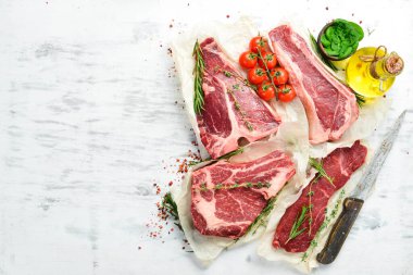 Çiğ biftek seti: biftek, striploin, pirzola, New York bifteği. Üst Manzara. Beyaz ahşap arka planda.