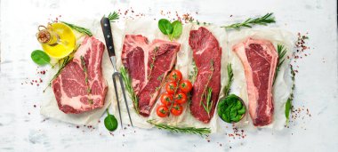 Çiğ biftek seti: biftek, striploin, pirzola, New York bifteği. Üst Manzara. Beyaz ahşap arka planda.