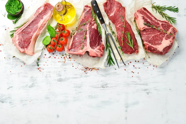 Çiğ biftek seti: biftek, striploin, pirzola, New York bifteği. Üst Manzara. Beyaz ahşap arka planda.