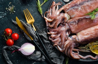 Siyah taş tabakta çiğ deniz mürekkep balığı pişmeye hazır. Üst Manzara. Karanlık bir arka planda.