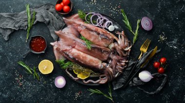Siyah taş tabakta çiğ deniz mürekkep balığı pişmeye hazır. Üst Manzara. Karanlık bir arka planda.