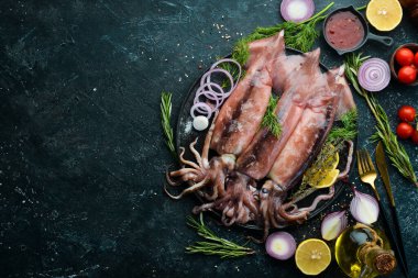 Siyah taş tabakta çiğ deniz mürekkep balığı pişmeye hazır. Üst Manzara. Karanlık bir arka planda.