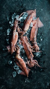 Siyah taşlı arka planda buzdaki mürekkep balığı. Deniz ürünleri. Karanlık bir arka planda.